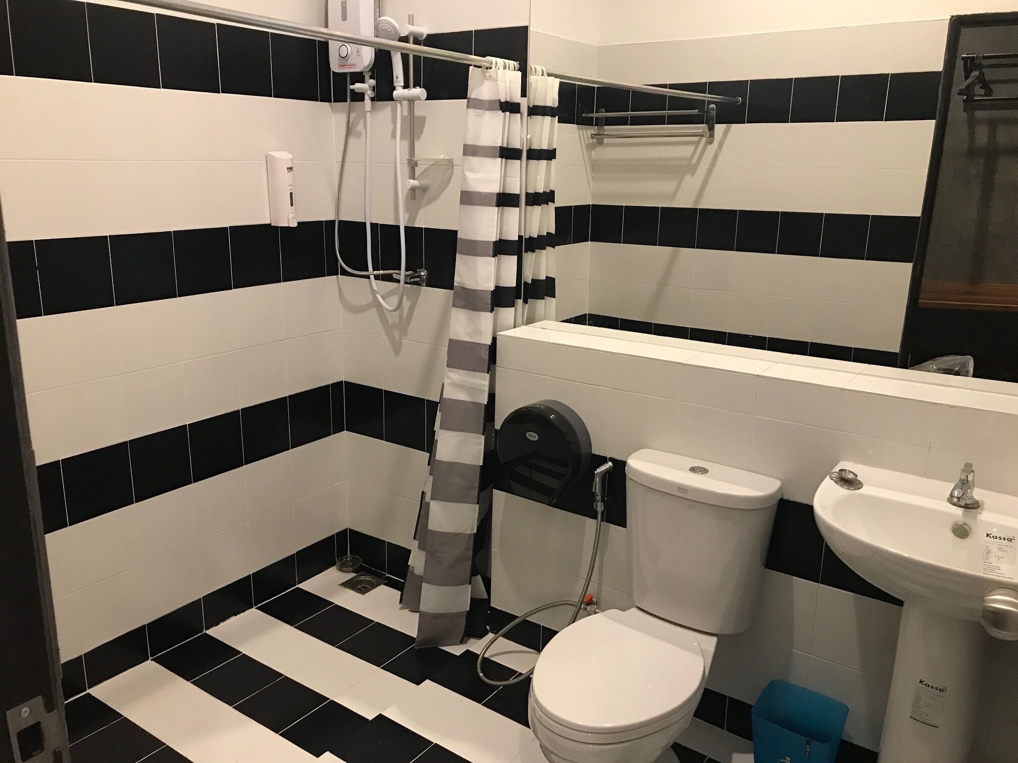 A bathroom with a toilet, sink, and shower. The floor has black and white tiles.