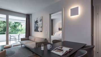 Habitació d'hotel moderna amb un sofà, una taula de menjador i una finestra gran que ofereix vistes a zones verdes.