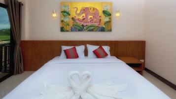 A hotel room with a large bed, a wooden headboard, and a painting of an elephant.