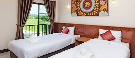 A hotel room with two beds, a large window with curtains, a painting on the wall, and an air conditioning unit.