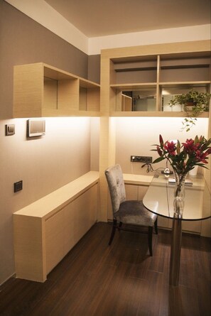Un comedor moderno con una mesa de vidrio, una silla acolchada y un jarrón con flores.