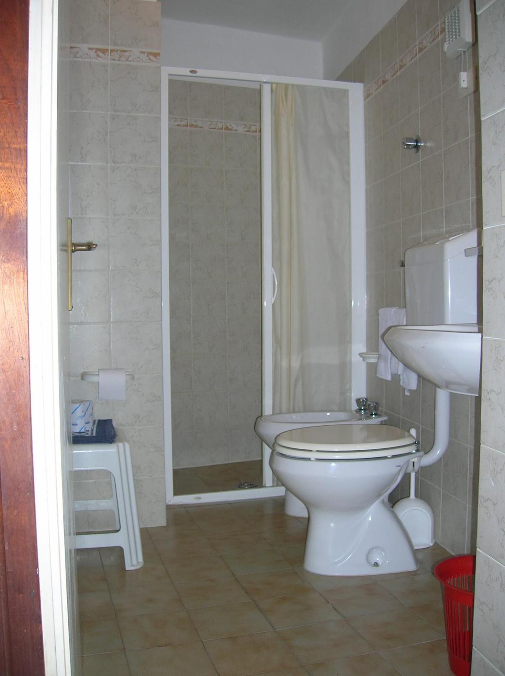 A bathroom with a toilet, a shower enclosure, and a sink.
