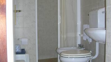 A bathroom with a toilet, a shower enclosure, and a sink.
