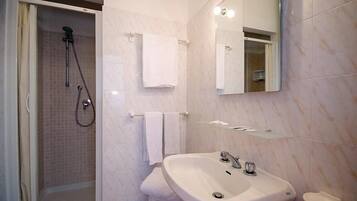 A bathroom with a shower, sink, and mirror.