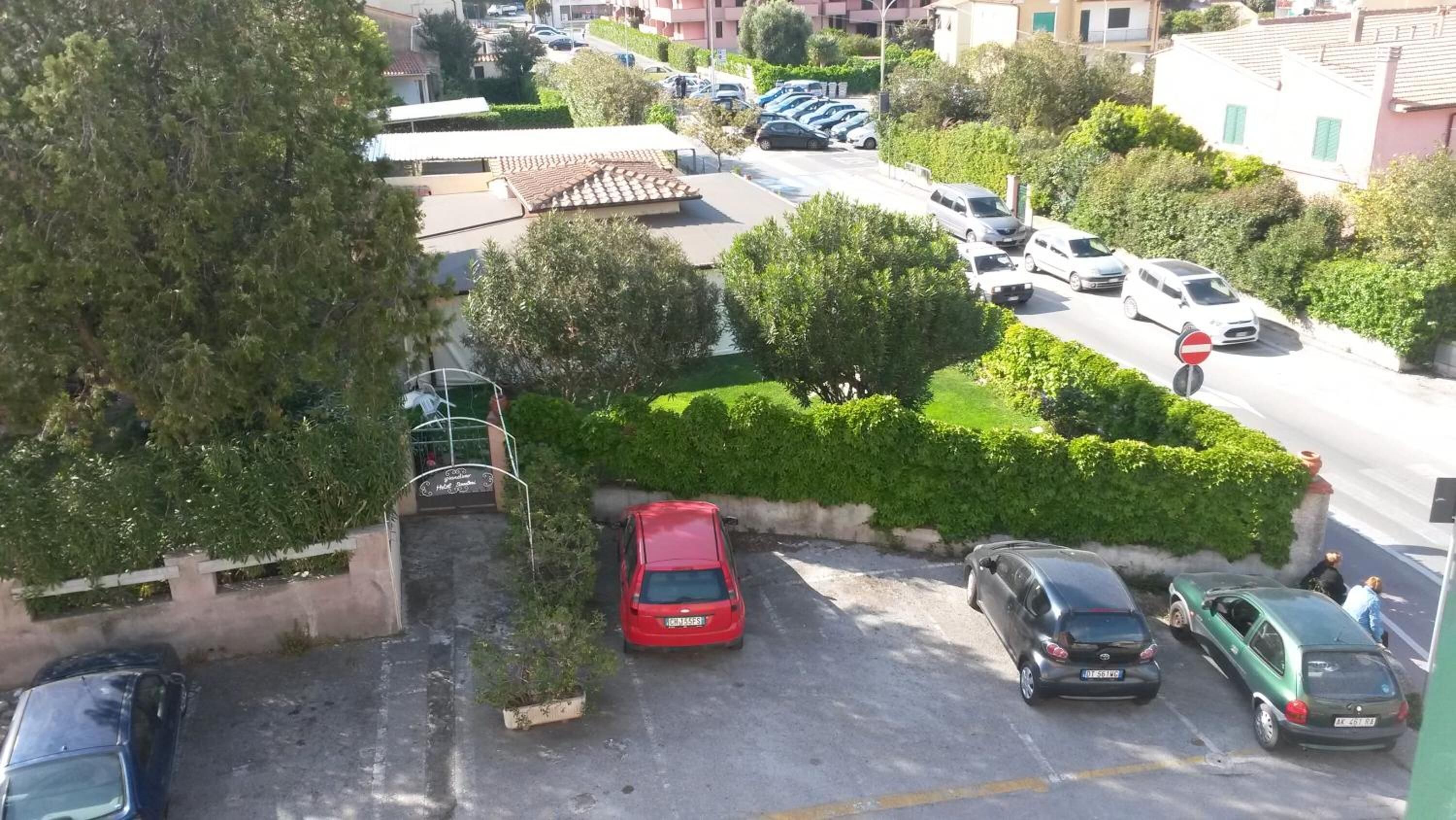 Zona residencial amb cotxes aparcats, una entrada tancada i un edifici amb teulada de rajola.