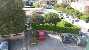 Una zona residencial con coches estacionados, un acceso con portón y un edificio de techo a ladrillo.