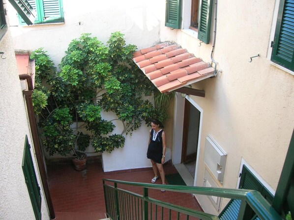 A narrow courtyard with a tiled roof, potted plants, and a staircase leading to an upper level. - Hotel Anselmi (Marciana Marina)