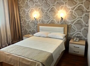Habitación de hotel con cama, dos mesitas de noche y una pared con diseño decorativo.