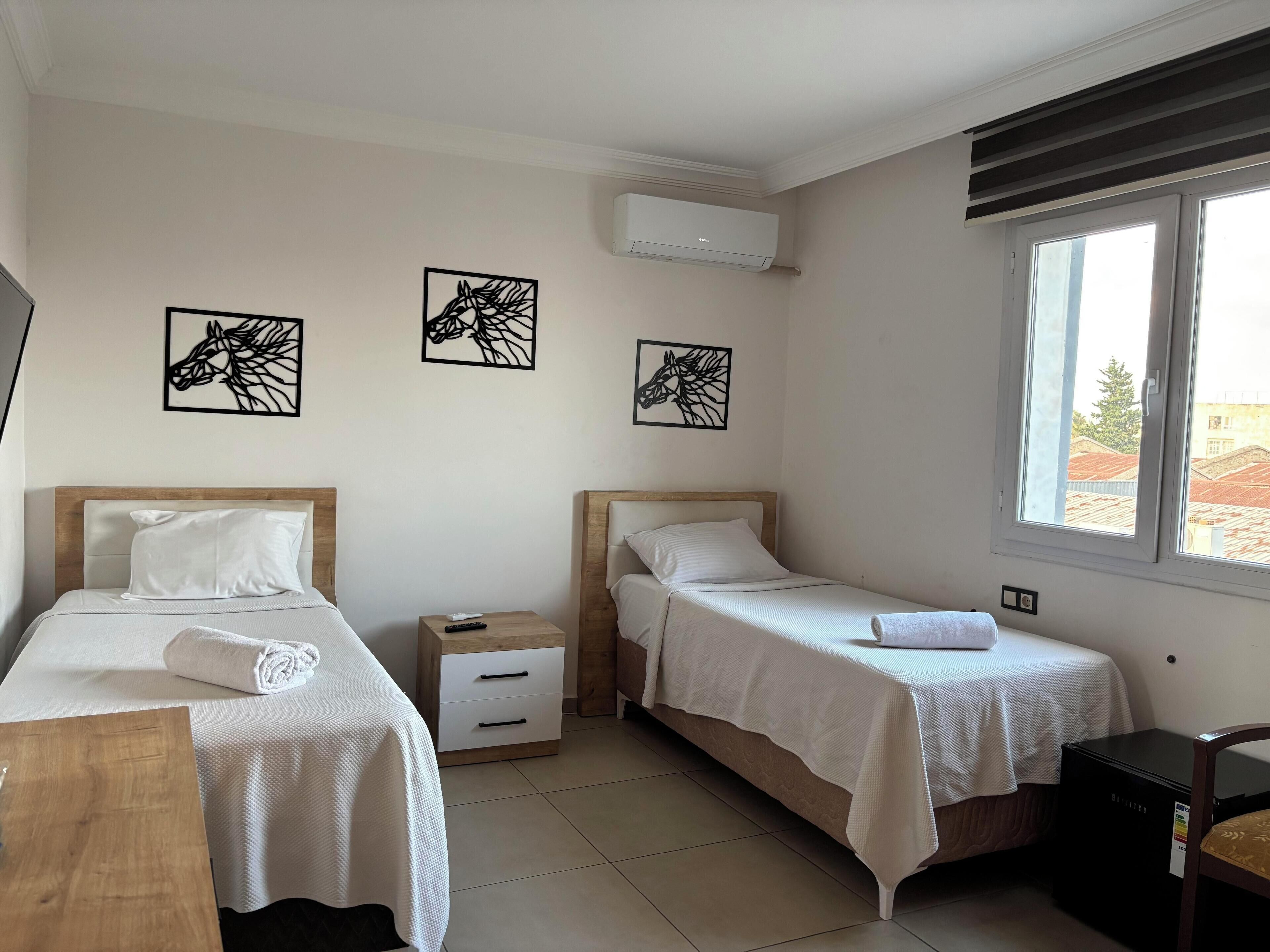 Una habitación de hotel con dos camas, un escritorio y una ventana.