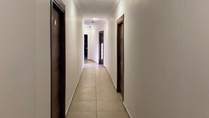 A long, narrow hallway with white walls and wooden doors on either side.