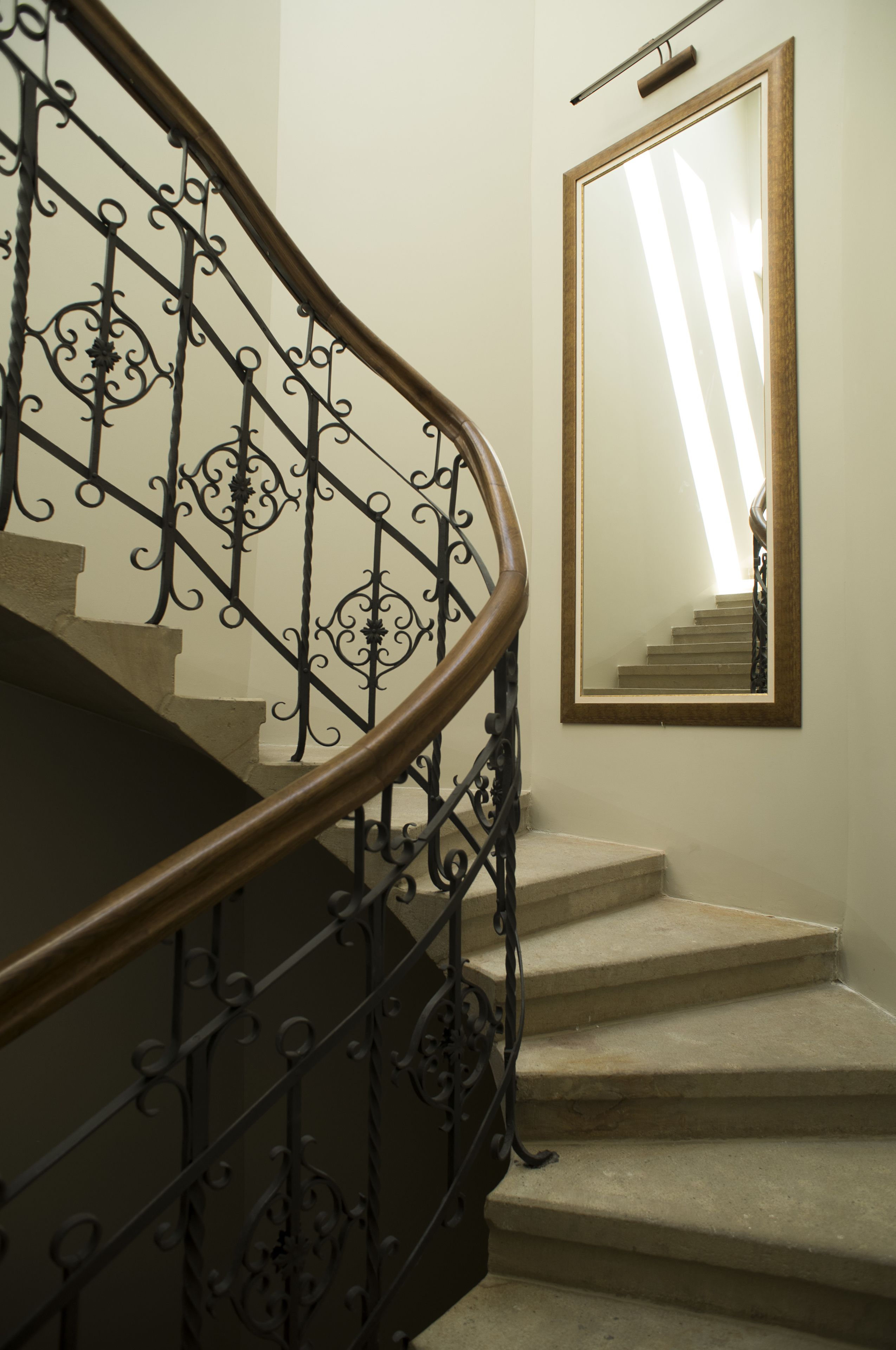 A staircase with ornate metal railings and a mirror on the wall.