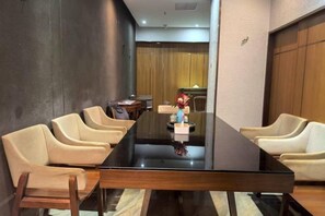 A conference room with a long table, multiple chairs, and a small table with a vase. - Mint Appart International Hotel (Shenzhen Convention and Exhibition Center) (Shenzhen)