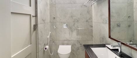 A modern bathroom with a toilet, sink, and shower.