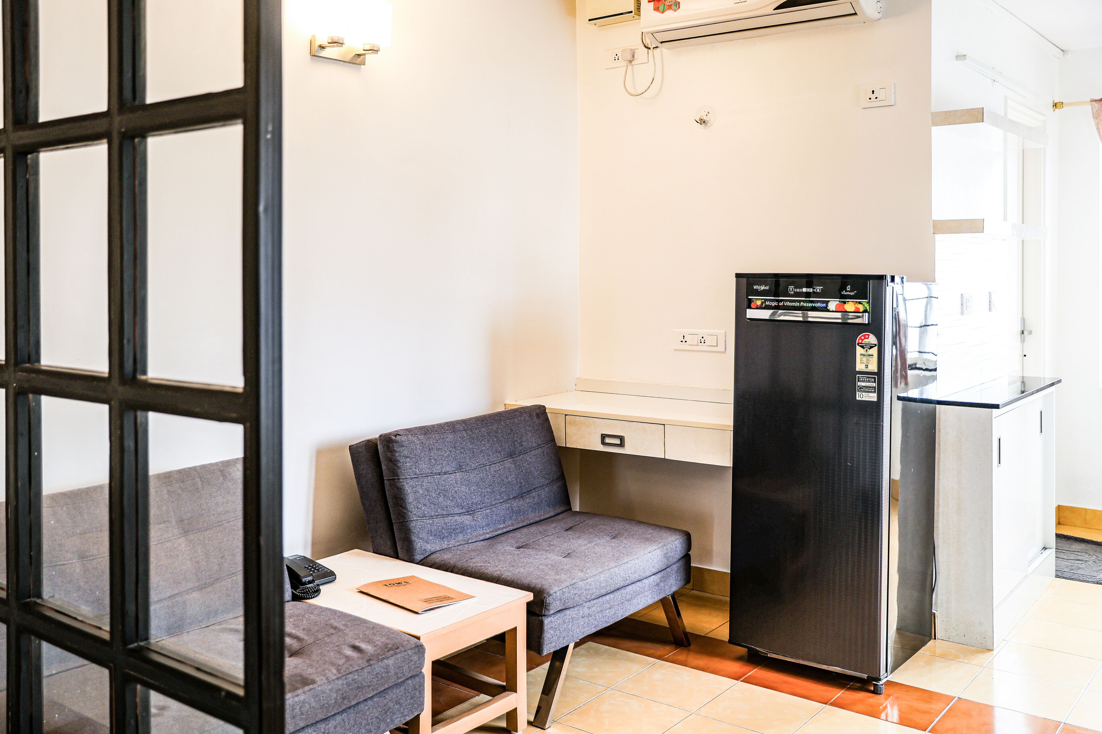 Una kitchenette compacta con refrigerador, una mesita y una silla.