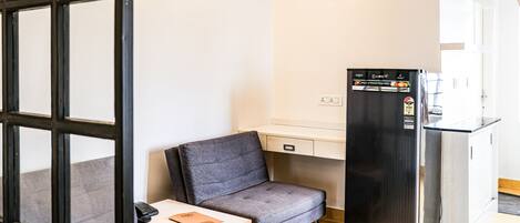 A compact kitchenette with a refrigerator, a small table, and a chair.
