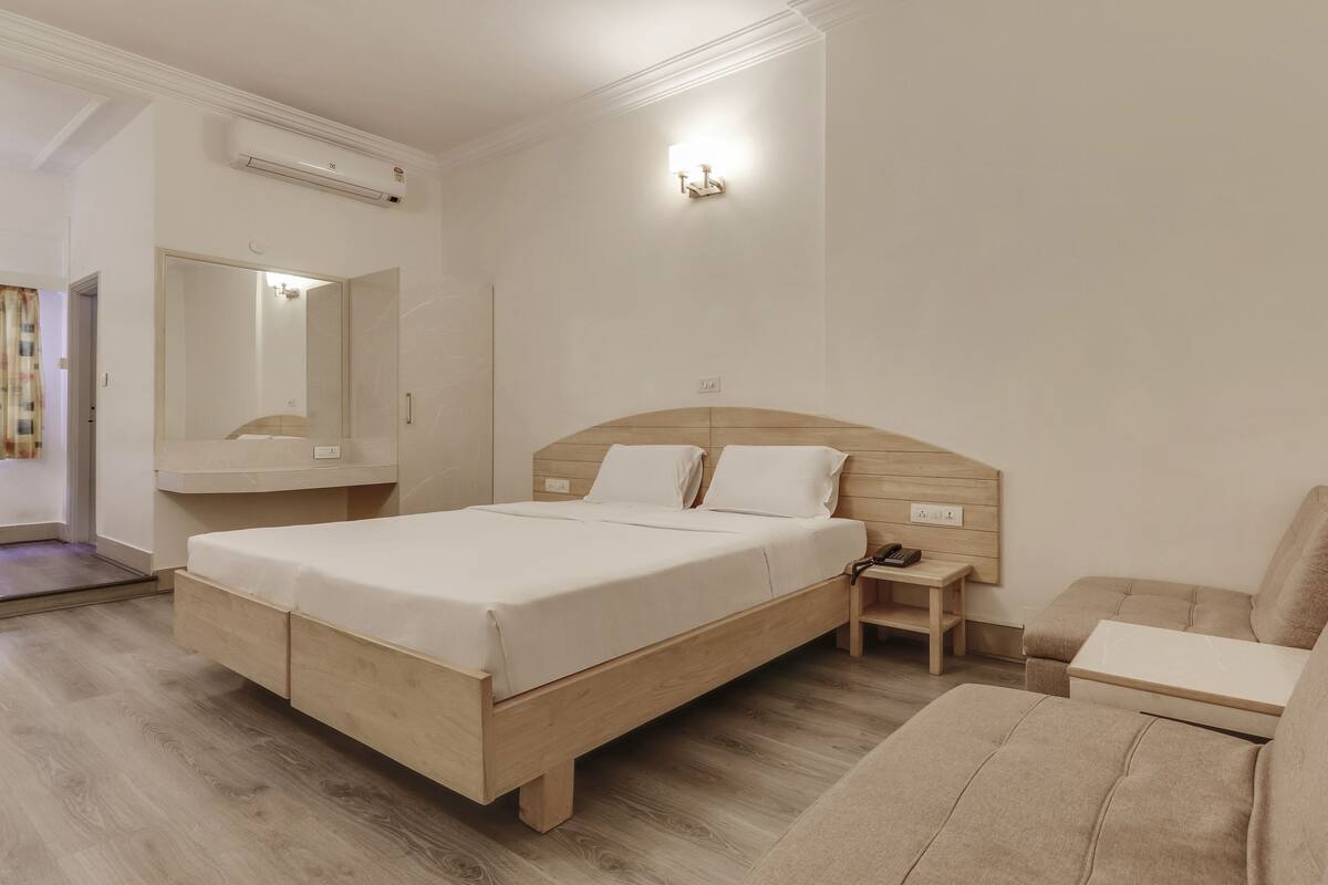 Une chambre d’hôtel comprenant un lit, une table de chevet, une commode et un canapé.