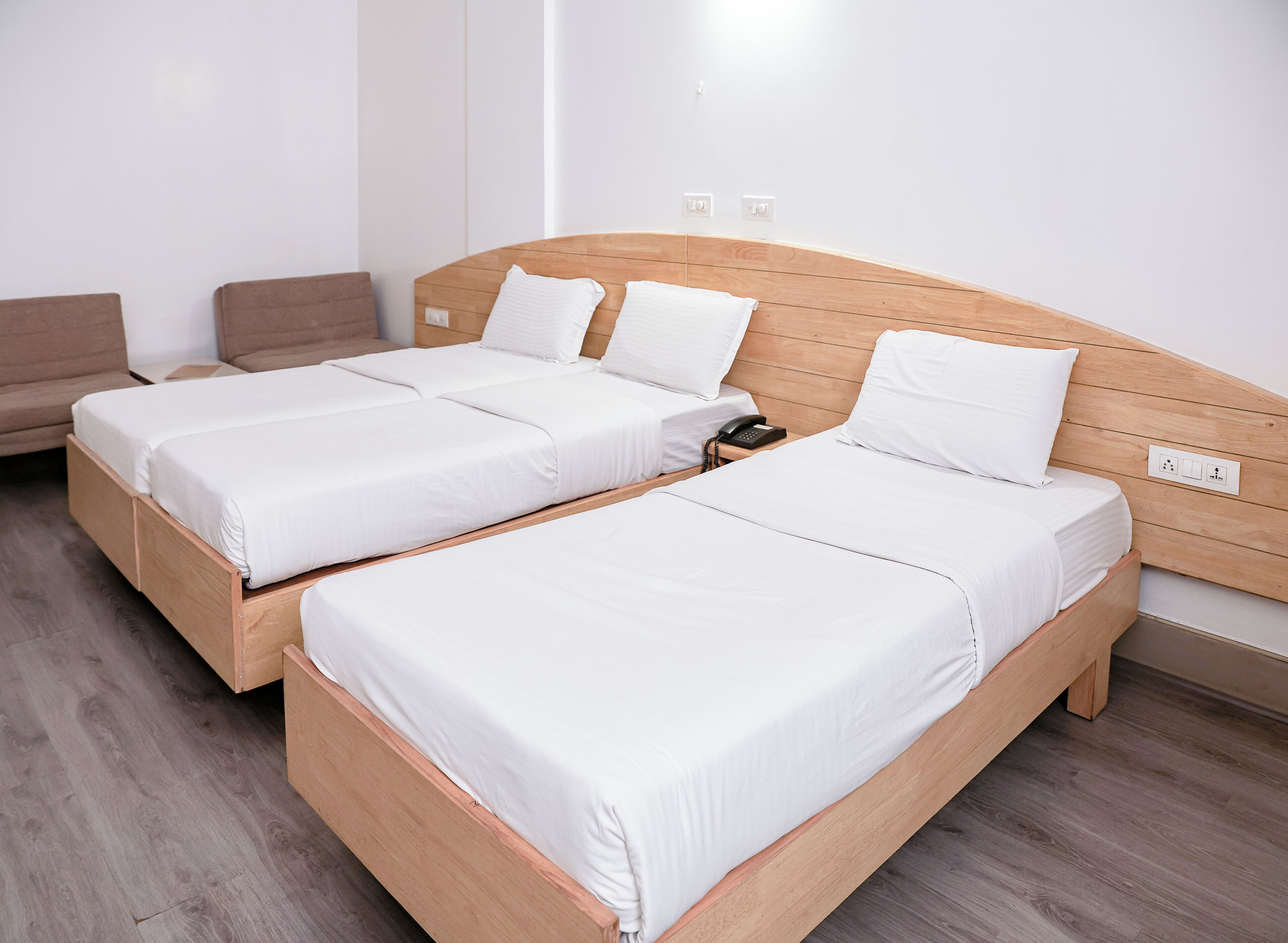 Habitación de hotel con dos camas individuales, cabecera de madera, teléfono en la mesita de noche y una pequeña mesa auxiliar.