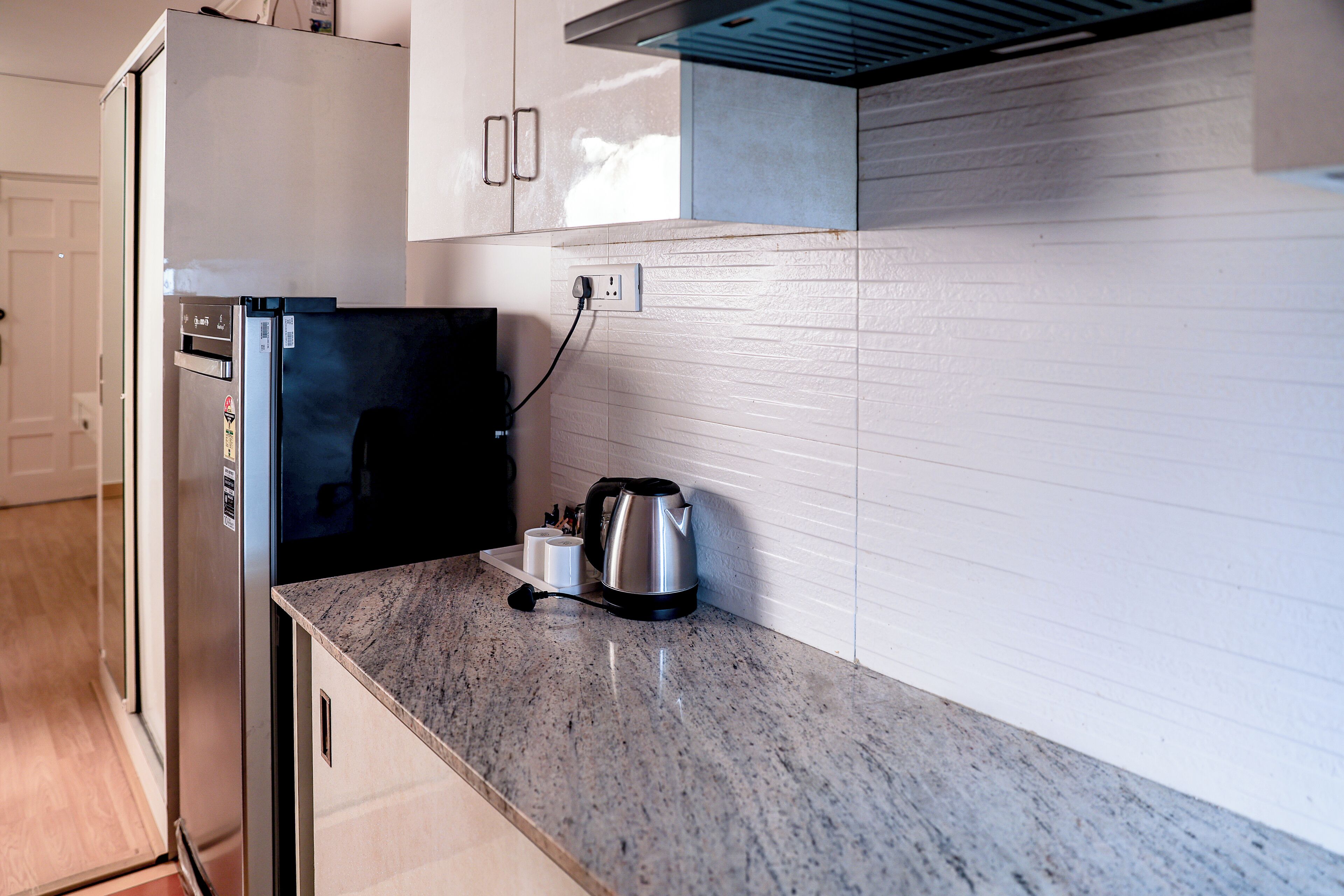 A kitchen with a stainless steel refrigerator, a kettle, and a countertop.