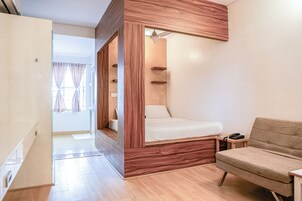 A modern bedroom with a wooden bed frame, a sofa, and a bedside table with a phone.