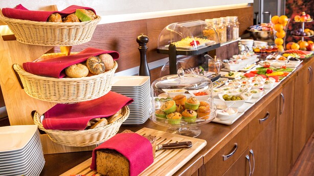 A buffet with various food items, including breads, muffins, and fruits.
