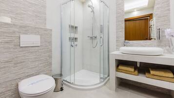 A modern bathroom with a glass-enclosed shower, a white toilet, and a vanity with a sink and towel racks.