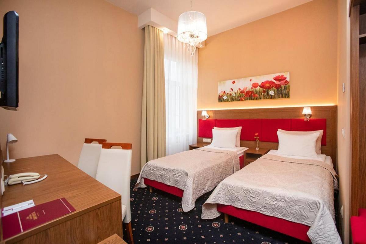 Quarto de hotel com duas camas, uma escrivaninha, telefone e um quadro na parede.