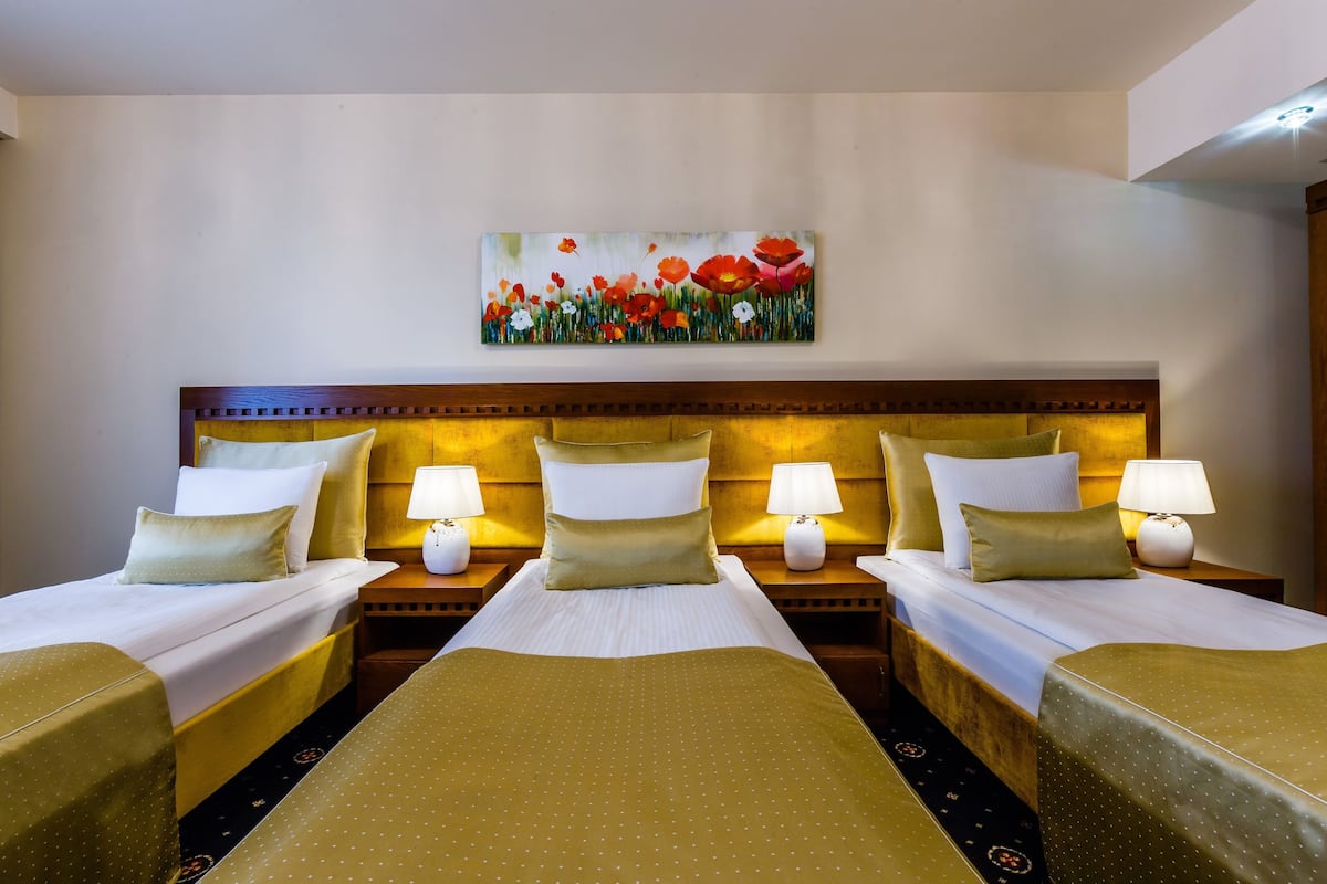 Quarto de hotel com uma cama grande, duas mesas de cabeceira e um quadro na parede.