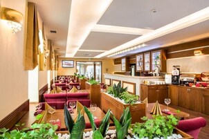 Un restaurante con asientos tapizados en rojo, mesas de madera y una zona de bar con diversas bebidas.