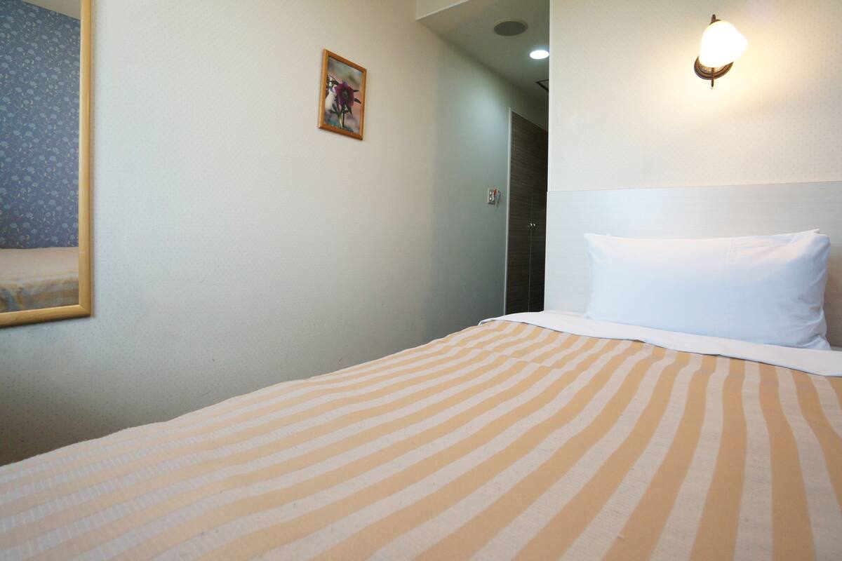 Una camera d'albergo con un letto, un quadro appeso al muro e un lampadario.