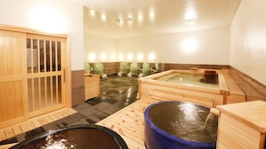 Un onsen japonès tradicional amb banyeres de fusta, una porta de fusta i un paviment de rajoles.