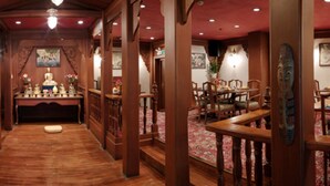Un interior tradicional con vigas de madera, un altar central y un comedor con sillas y mesas.