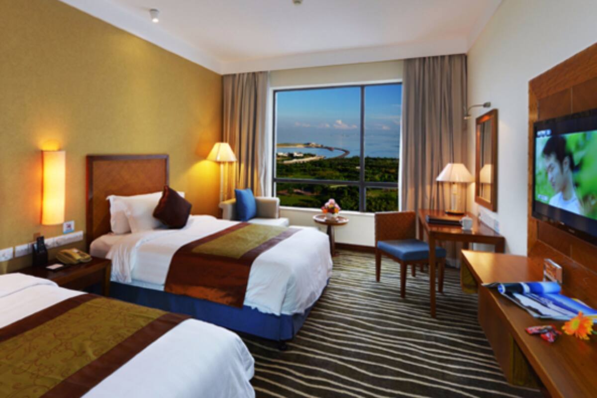 A hotel room with two beds, a desk, a TV, and a large window with a view.