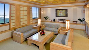 Un salón de estilo japonés tradicional con esteras de tatami, muebles de madera bajos y vista al mar a través de amplias ventanas.