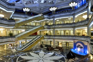 A multi-level atrium with marble floors, escalators, and a central water feature. - Baohua Harbour View Hotel (Haikou)
