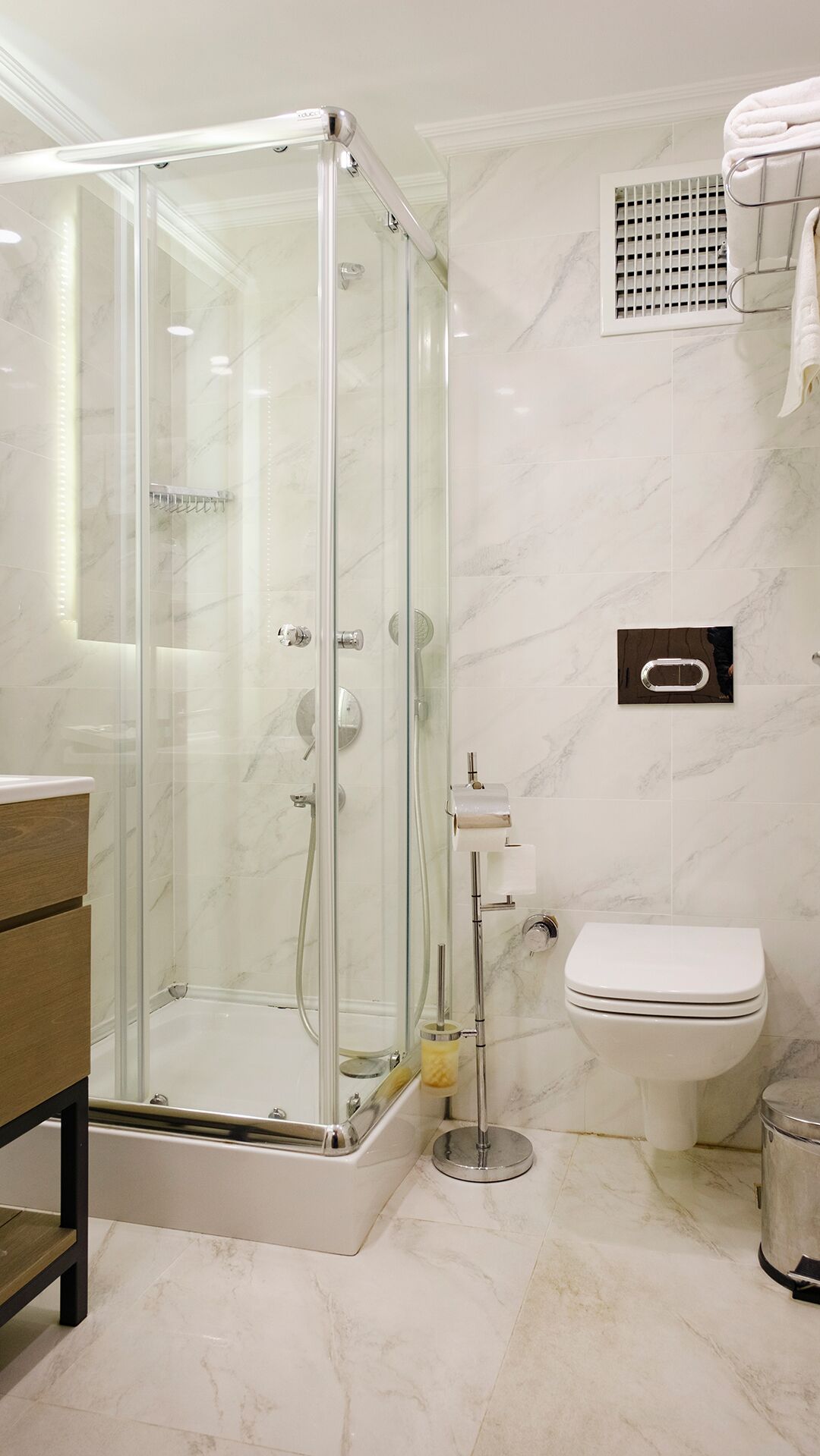 A modern bathroom with a glass-enclosed shower, a toilet, and a sink.