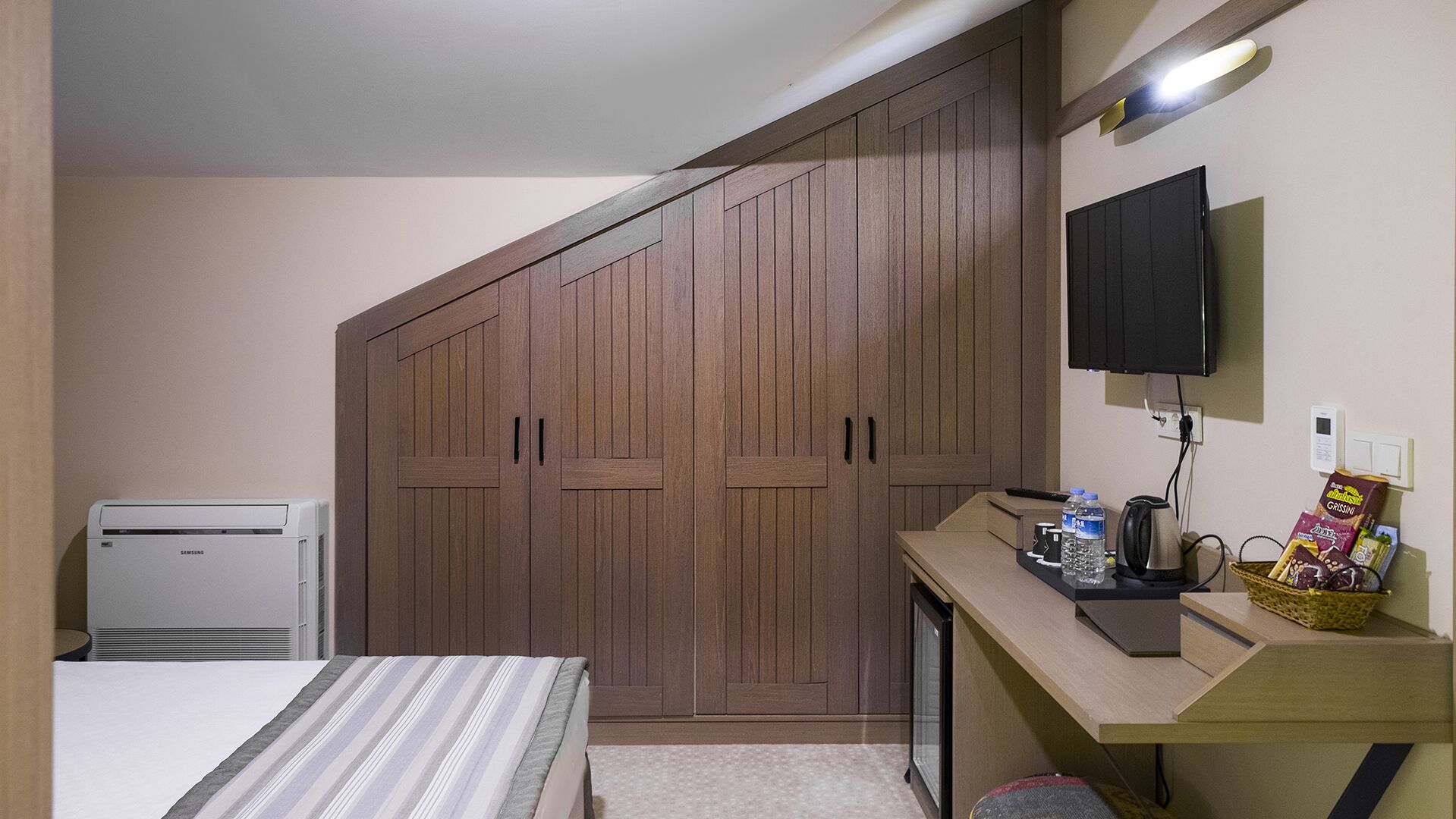 Quarto com um guarda-roupa espaçoso, uma cama, uma escrivaninha com computador, uma televisão e um pequeno aquecedor.