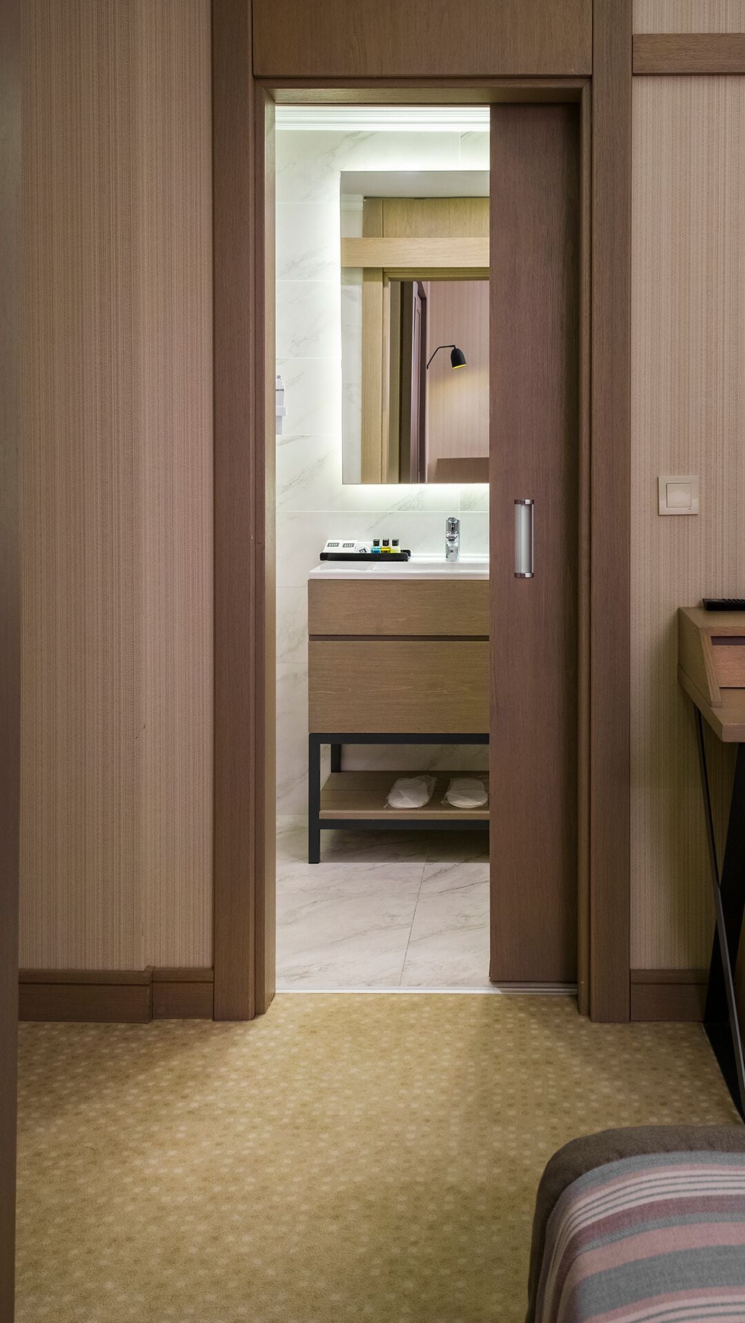 A walk-in closet with a wooden wardrobe, a mirror, and a small vanity with a sink and toiletries.