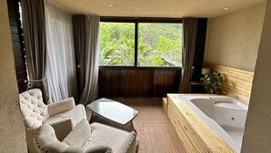 Una habitación con un ventanal grande, una bañera y un rincón de estar con una mesa y sillas.