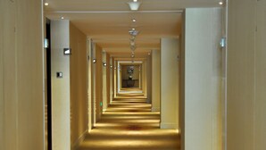 A long, narrow hotel corridor with a carpeted floor and a central light fixture. - Conifer Garden Hotel (Haikou)