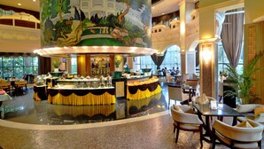 A spacious lobby with a central bar area, seating arrangements, and a large mural on the ceiling. - Conifer Garden Hotel (Haikou)