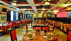A restaurant with multiple tables and chairs, each set with plates, bowls, and cutlery.