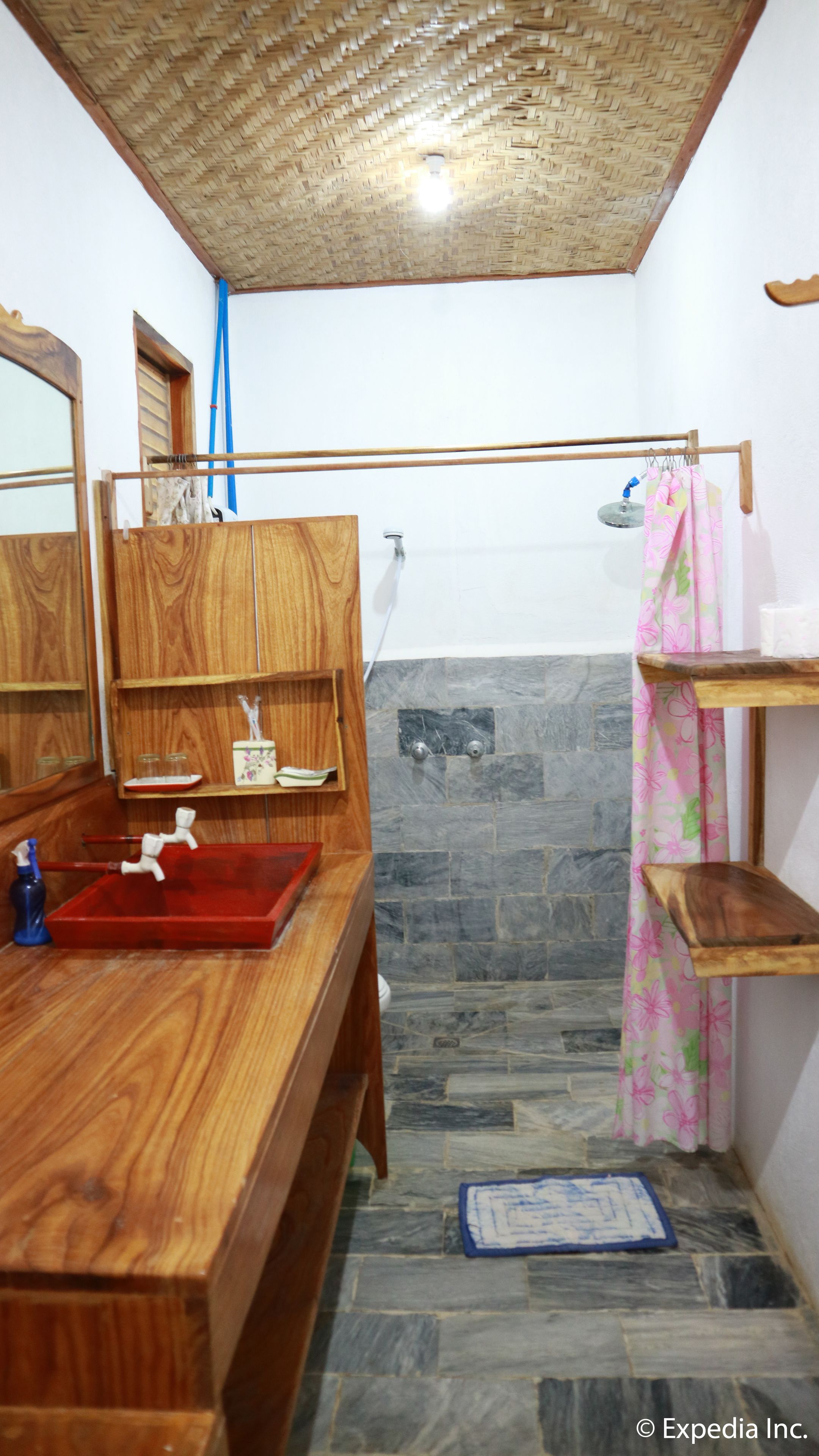 Un baño con tocador de madera, pared de ducha de piedra y cortina de ducha.