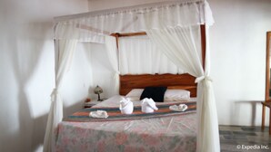 A four-poster bed with a floral bedspread and white curtains.