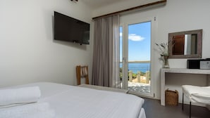 Une chambre d’hôtel avec un lit, une télévision, un bureau, une chaise et une vue sur la mer.