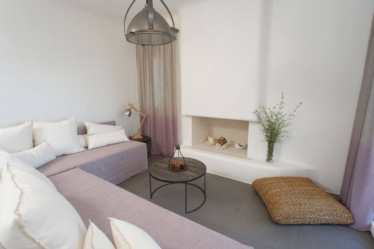 Un salon moderne comprenant un canapé, une petite table ronde, un lampadaire, une cheminée et un vase décoratif.