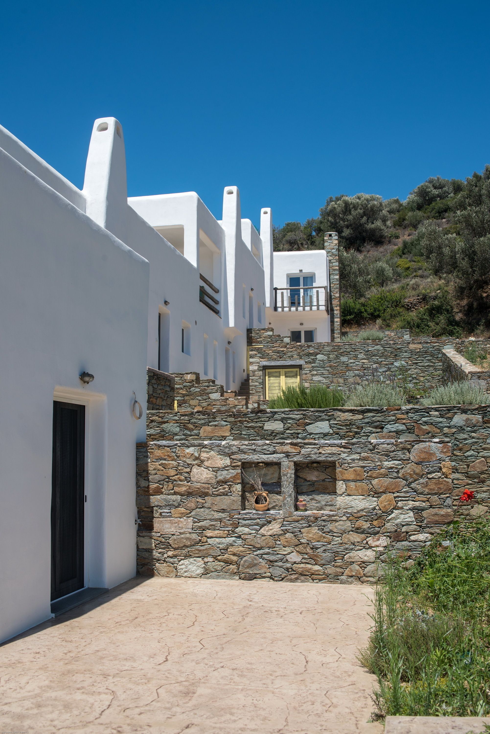 A white building with stone walls and a clear blue sky.