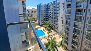 Um edifício alto com piscina e vegetação ao redor.