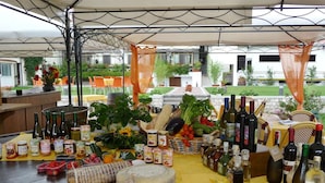Een tafel gedekt met eten, drinken en toevoegingen in een overdekt buitengebied.