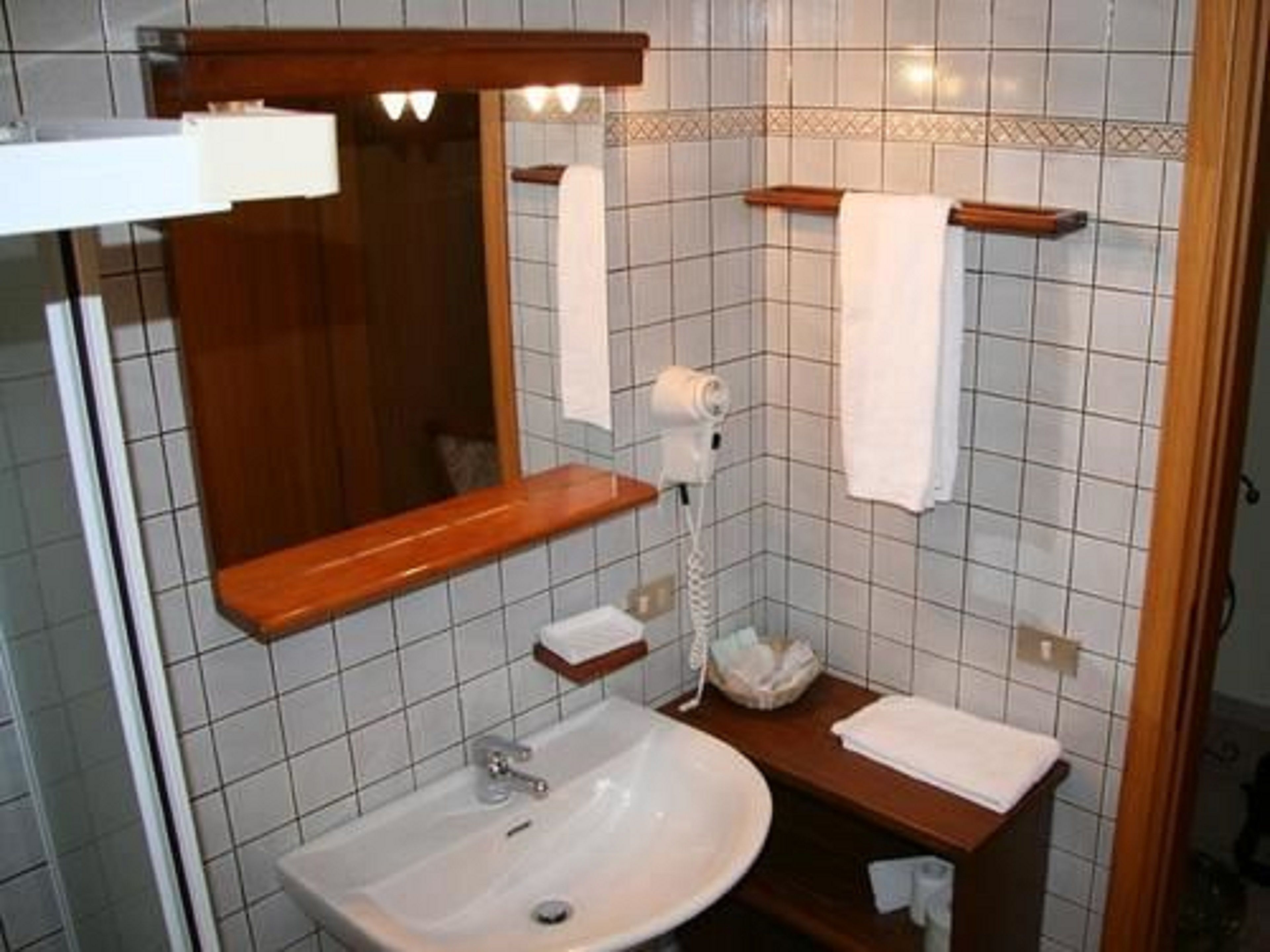 A bathroom with a sink, mirror, towel rack, and a hairdryer.