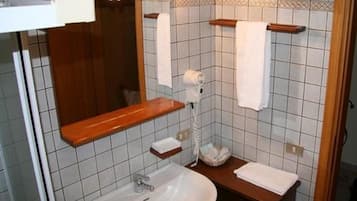 Ett badrum med handfat, spegel, handdukshängare och en hårtork.